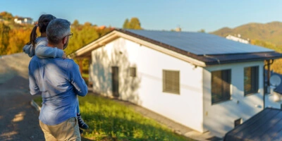 Ojciec z córką patrzący na dom z panelami solarnymi na dachu